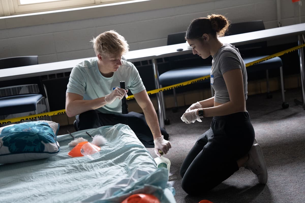 Two students investigating a crime scene using a flashlight