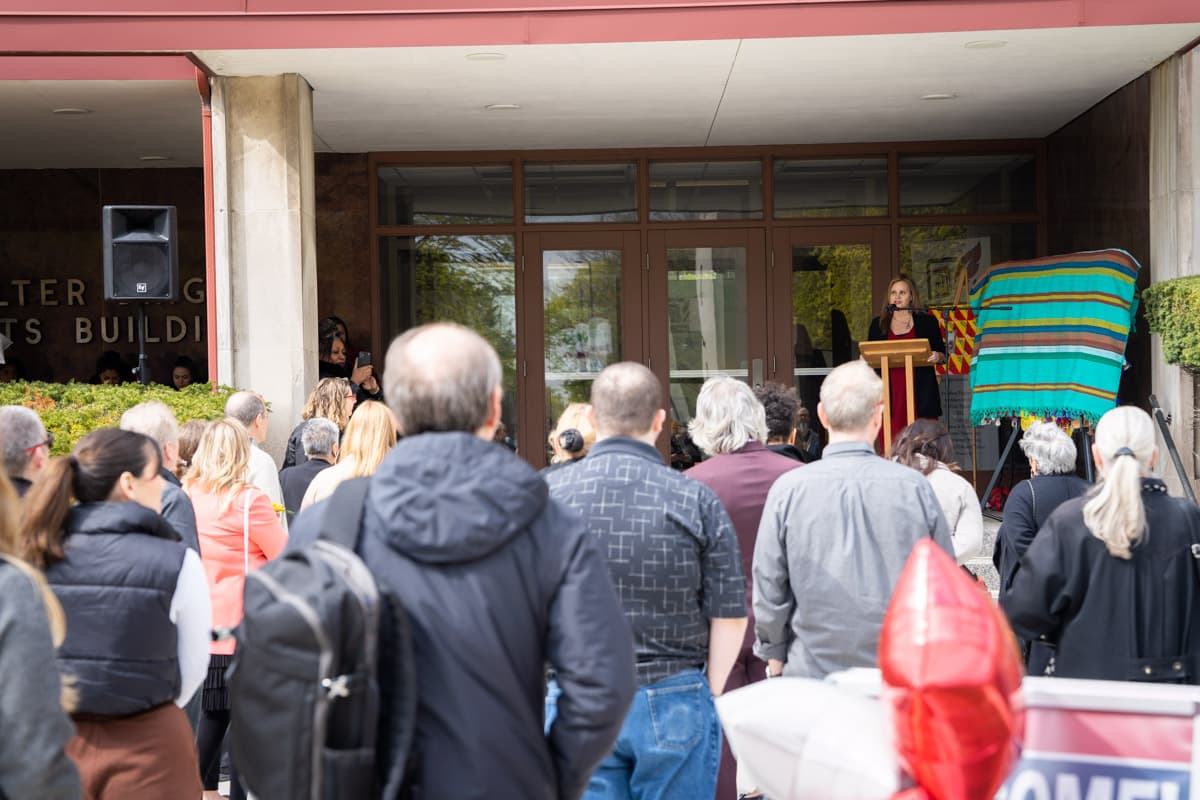 Lara Wasner speaking in front of a group of people during the Healing Wall Panel 5 unveiling