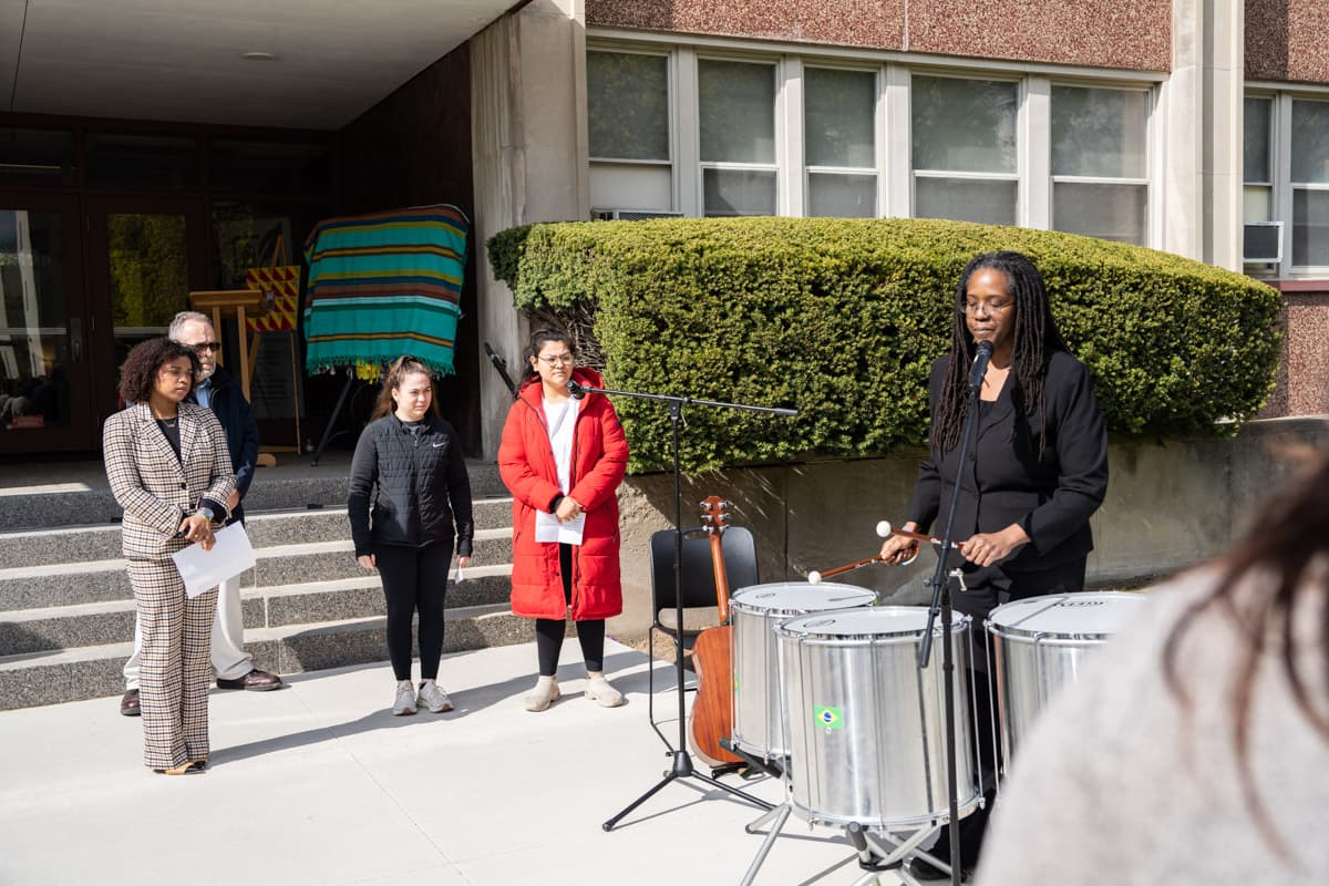 Musician playing drums with a group of people during the Healing Wall Panel 5 unveiling