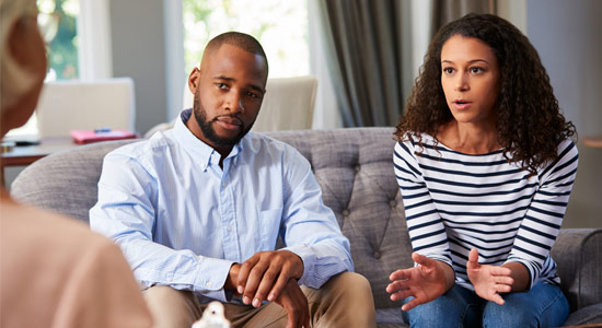 photo of a male/femle couple on the couch speaking with a counselor